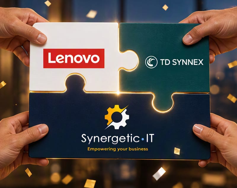 Four hands hold three connected puzzle pieces carrying the Lenovo, TD SYNNEX and Synergetic IT logos, with a warm golden glow along the seams and gold confetti in an office at dusk.
