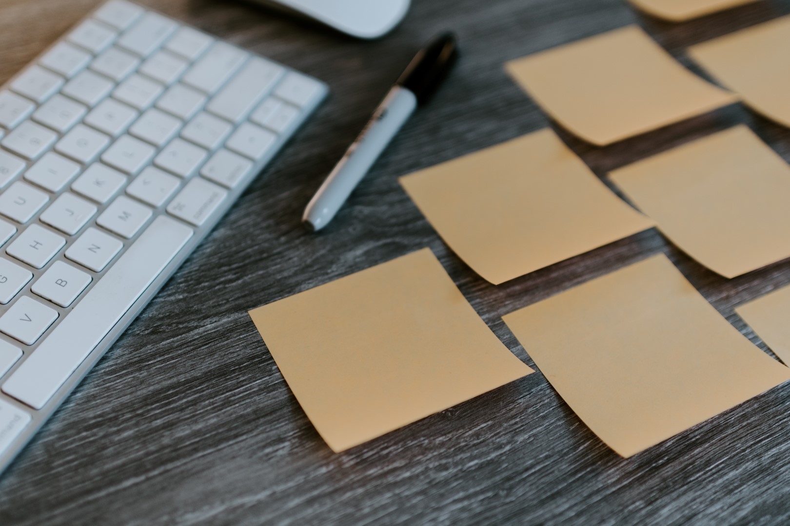 A computer keyboard, a permanent marker and a couple of yellow post-its representing the step-by-step agile way of working.